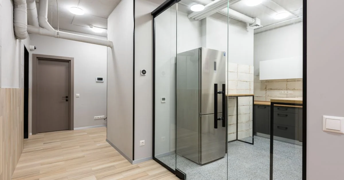 Intérieur élégant et contemporain mettant en valeur un espace cuisine avec une cloison en verre et des appareils modernes.