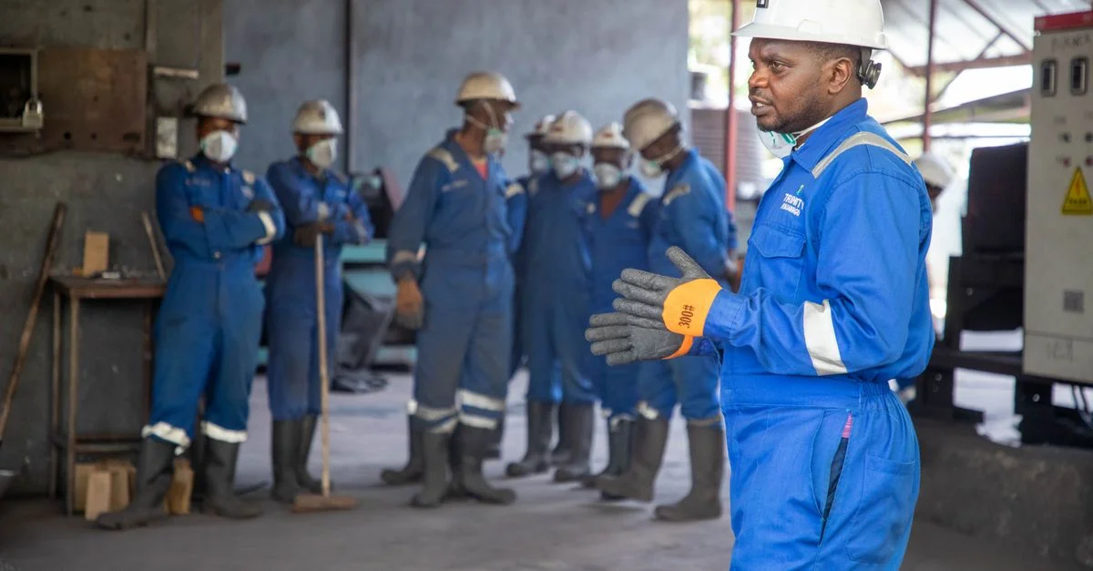 Un groupe d'ouvriers d'usine en tenue de sécurité suivent une formation en intérieur.