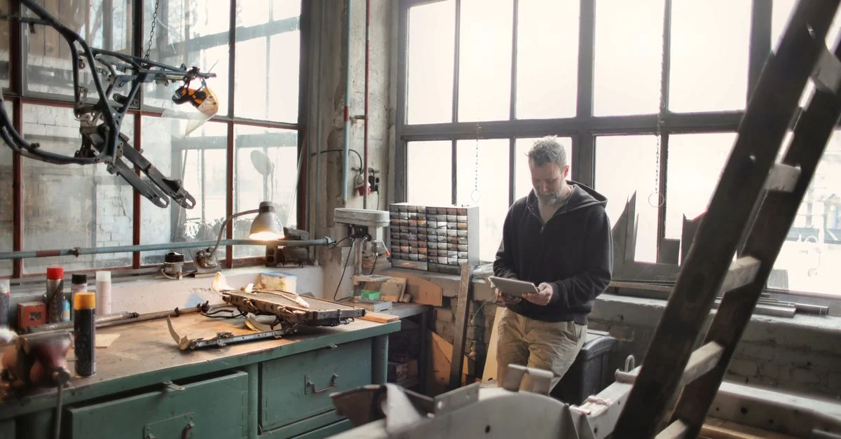 Technicien dans un atelier industriel utilisant une tablette pour la gestion du travail technique.