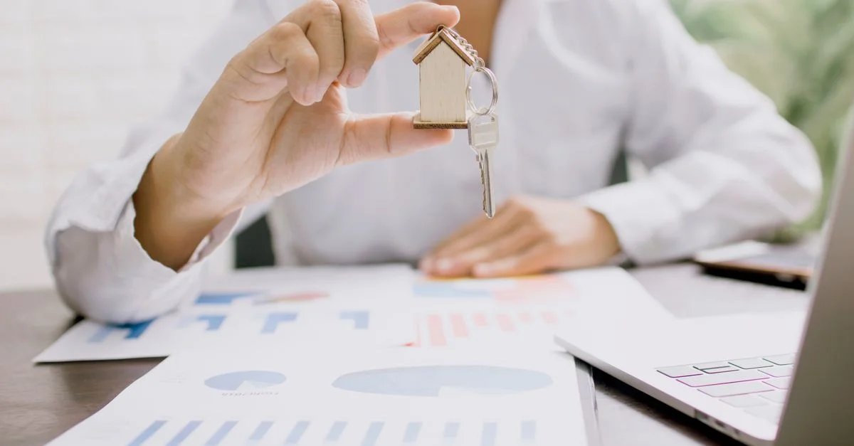 Professionnelle de l'immobilier présentant un modèle de maison avec des clés, symbolisant l'investissement et la propriété.