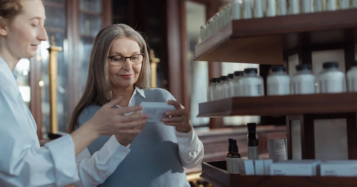 Femme âgée recevant de l'aide d'un pharmacien dans une pharmacie avec des rayons de produits.