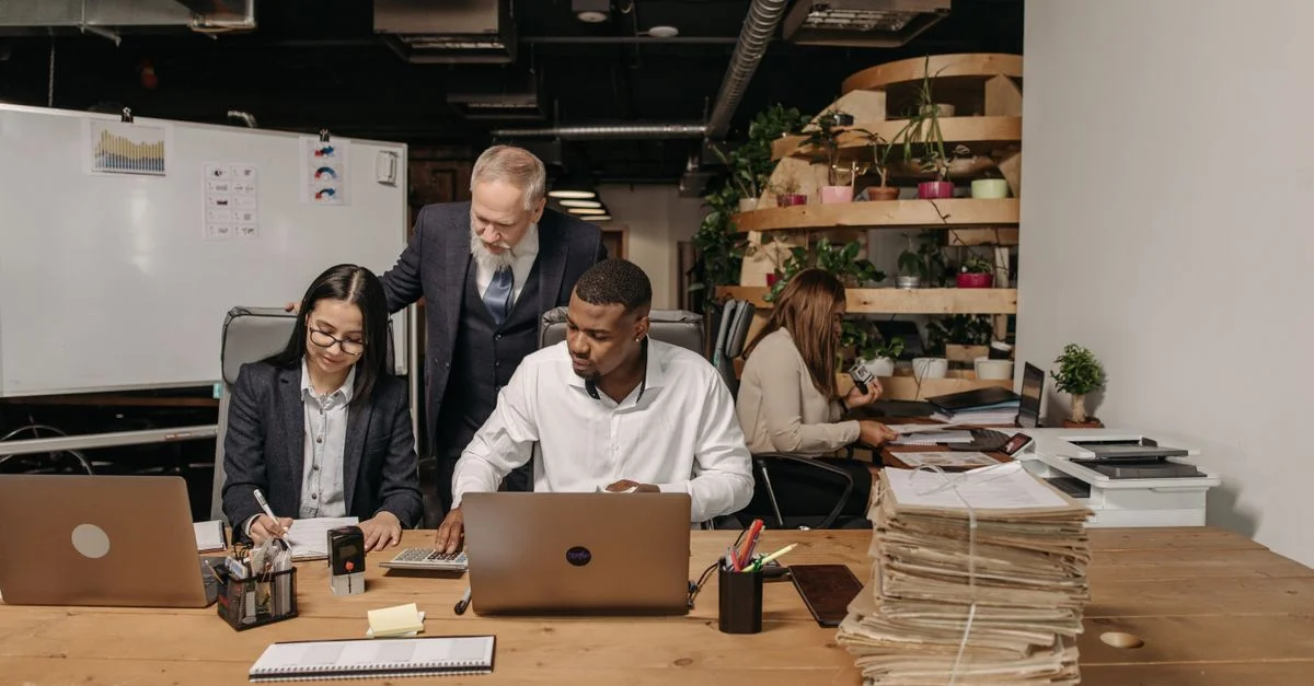 Équipe de professionnels travaillant en collaboration dans un environnement de bureau moderne avec des documents et des ordinateurs portables.